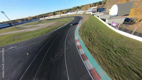 aerial filming of a circuit race on an asphalt circuit, fpv drone, racing cars go fast, time trials, sharp turns