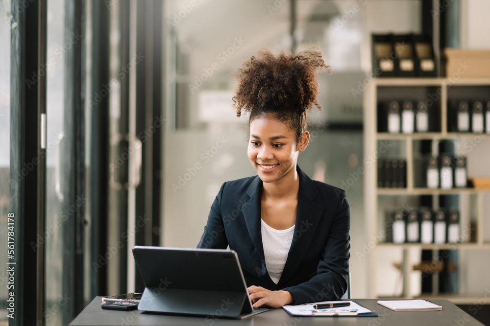 Young beautiful woman typing on tablet and laptop while sitting at the working table office Young beautiful woman typing on tablet and laptop while sitting at the working table office