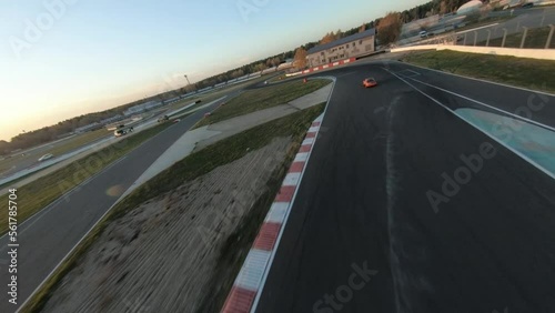aerial filming of a circuit race on an asphalt circuit, fpv drone, racing cars go fast, time trials, sharp turns