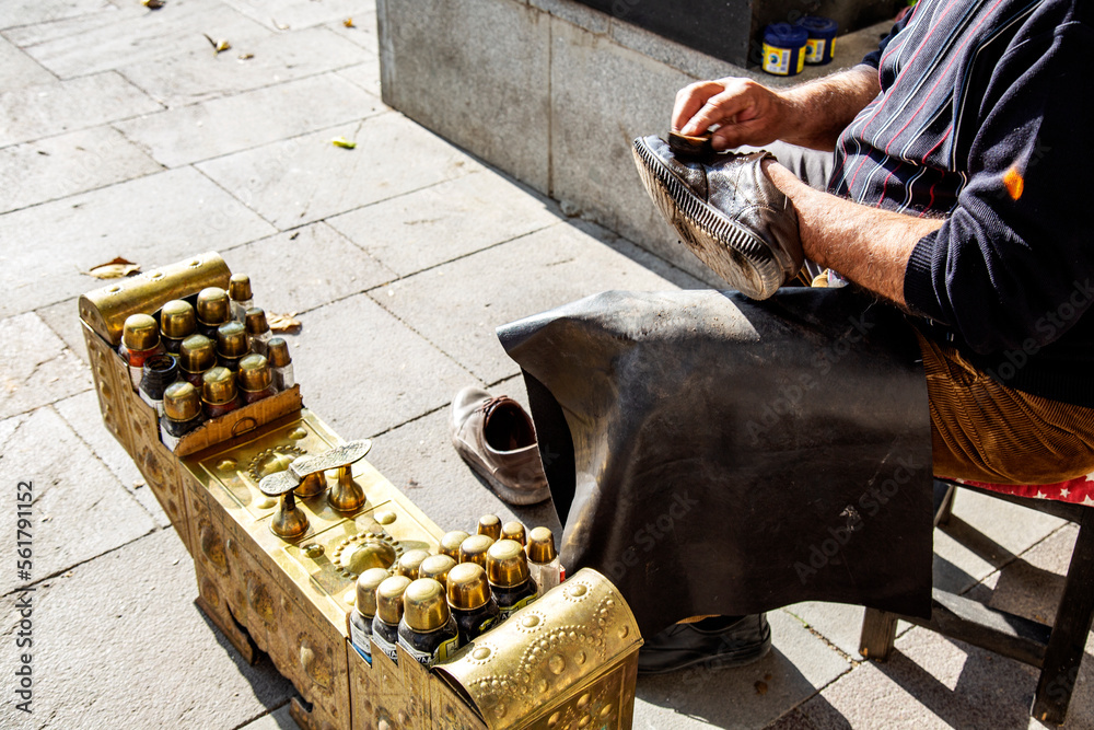 Man is cleaning shoes on the street in sunny day outdoor with special tools for painting and cleaning shoes, Turkish culture 