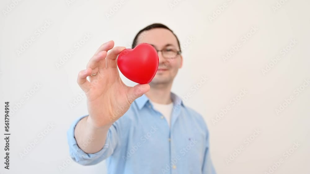 Portrait of funny man holding small red heart, looking at camera with excited facial expression, romantic feelings. Valentines day,anniversary,charity Portrait of funny man holding small red heart, looking at camera with excited facial expression, romantic feelings. Valentines day,anniversary,charity