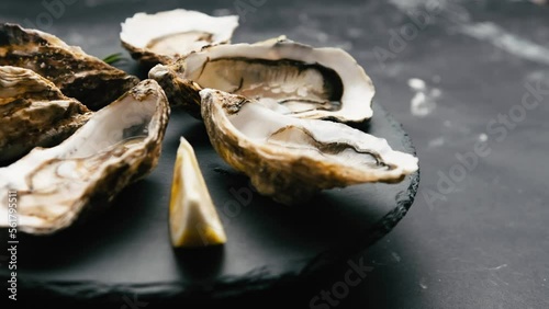 Raw luxury oysters with lemon and rosmarine for romantic dinner. Man and woman take seafood from platter photo