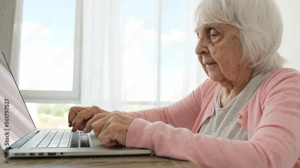 Senior woman typing on laptop keyboard. slowly at home. Elderly female person pushing notebook buttons and looking at screen Senior woman typing on laptop keyboard. slowly at home. Elderly female person pushing notebook buttons and looking at screen
