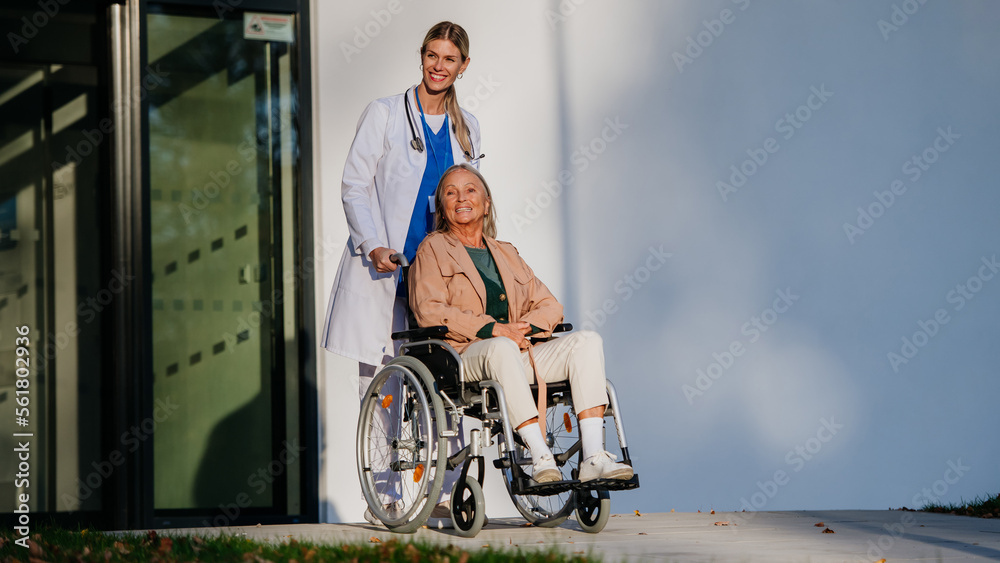 Young woman doctor taking care of senior woman at wheelchair.