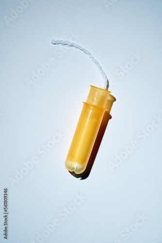 Women protection. Female yellow tampon with applicator on white background.