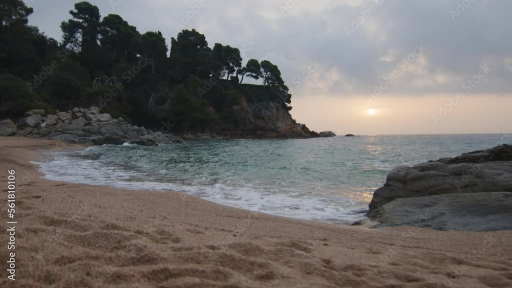 Steady shot at the edge of the wild beach at cloudy sunrise, in Spain