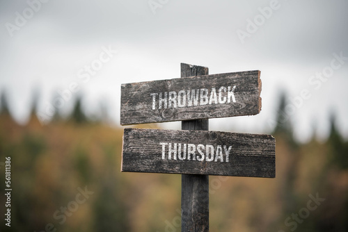 vintage and rustic wooden signpost with the weathered text quote throwback thursday, outdoors in nature. blurred out forest fall colors in the background. photo