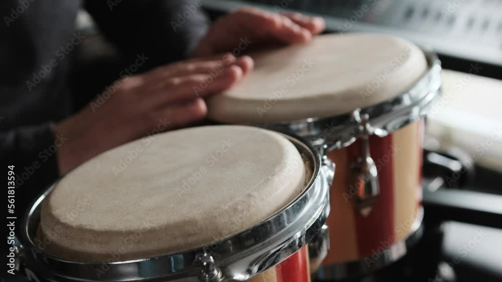 Musician playing hand Bongo Drums indoors closeup. Man with traditional ethnic folk music instrument Musician playing hand Bongo Drums indoors closeup. Man with traditional ethnic folk music instrument
