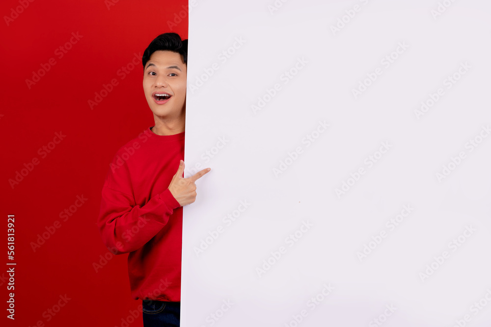 Handsome asian man wearing red casual clothes with hand pointing blank announcement banner in red background. Handsome asian man wearing red casual clothes with hand pointing blank announcement banner in red background.