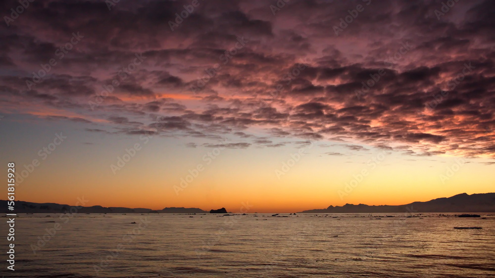 Pink popcorn clouds in an orange sky at sunset, at Cierva Cove, Antarctica