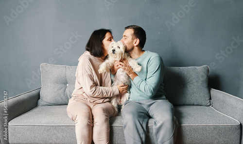Young couple cuddling and kissing their dog