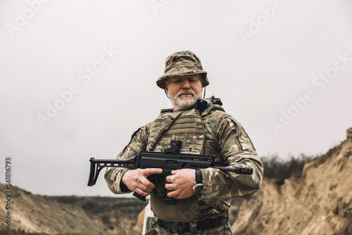 Mature soldier with a rifle in hands on a shooting range