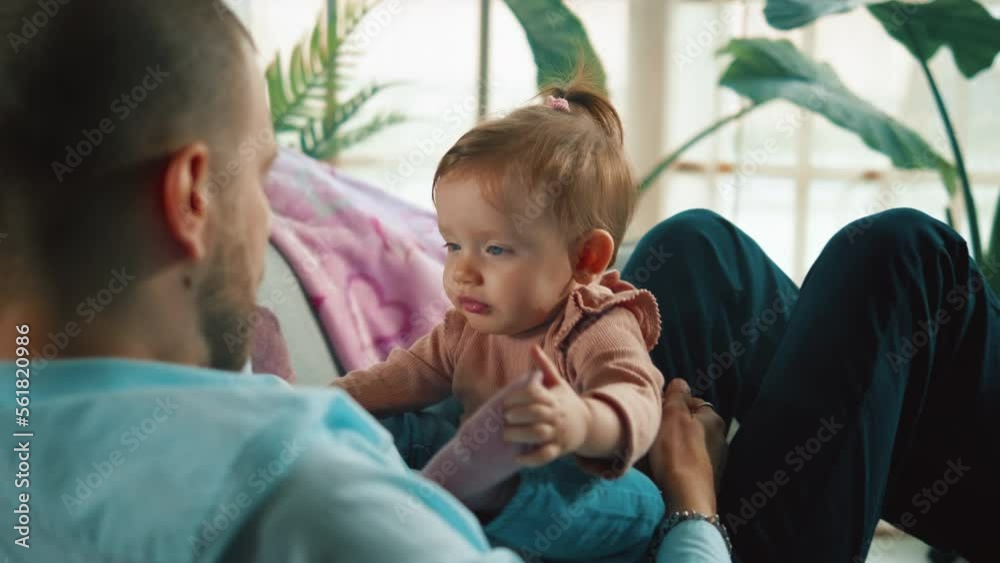 Beautiful blue eyes of a little infant girl looking at her father while playing on the couch at home Beautiful blue eyes of a little infant girl looking at her father while playing on the couch at home