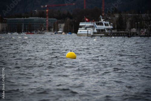 Yellow plastic buoy or buoys floating on a lake water in Switzerland, Europe. Close up telephoto shot, no people