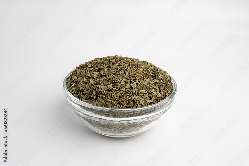 basil dry leaves in a glass dish on a white background basil dry leaves in a glass dish on a white background