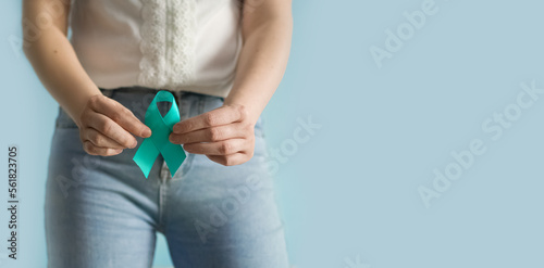 Woman holds in his hand Teal ribbon. Symbolic for cervical cancer, ovarian cancer, gynecological cancer and PCOS. And sexual assault awareness. Women's health care
