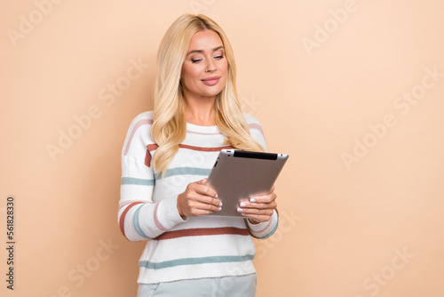 Photo of young woman hold tablet apple ipad browsing reading ebook online for free need just internet connection isolated on beige color background