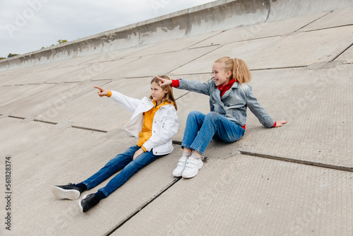 Two schoolmates relax and have fun on concrete embankment.