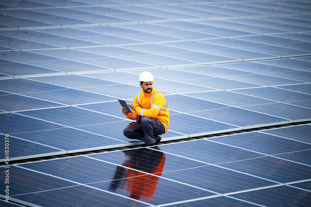 Engineer inspector holding laptop and working in solar panels power plant checking photovoltaic cells and electricity production. - obrazy, fototapety, plakaty 