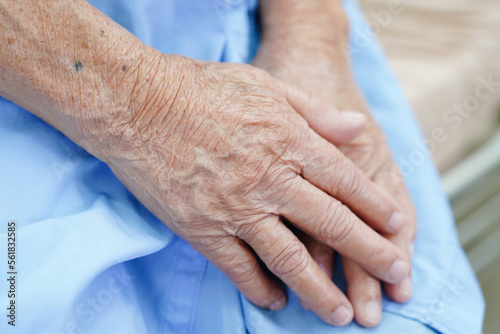 Asian elder senior woman patient sitting on bed in hospital, closeup at her hand. © manassanant