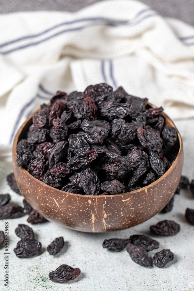 Dried black grapes on stone background. Dried grapes in coconut bowl. Nuts varieties. Healthy eating. close up Dried black grapes on stone background. Dried grapes in coconut bowl. Nuts varieties. Healthy eating. close up