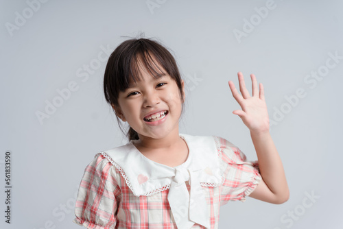 Cute friendly girl meeting new classmates, saying hi and hoping get along. Positive happy female child, raising palm in hello gesture, greeting cousine on playground, smiling joyfully