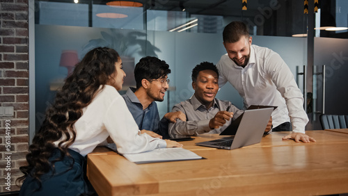 Business partners multiracial team group people workers in office looking at laptop happy with internet work success project opportunity multinational colleagues smiling receive notification offer