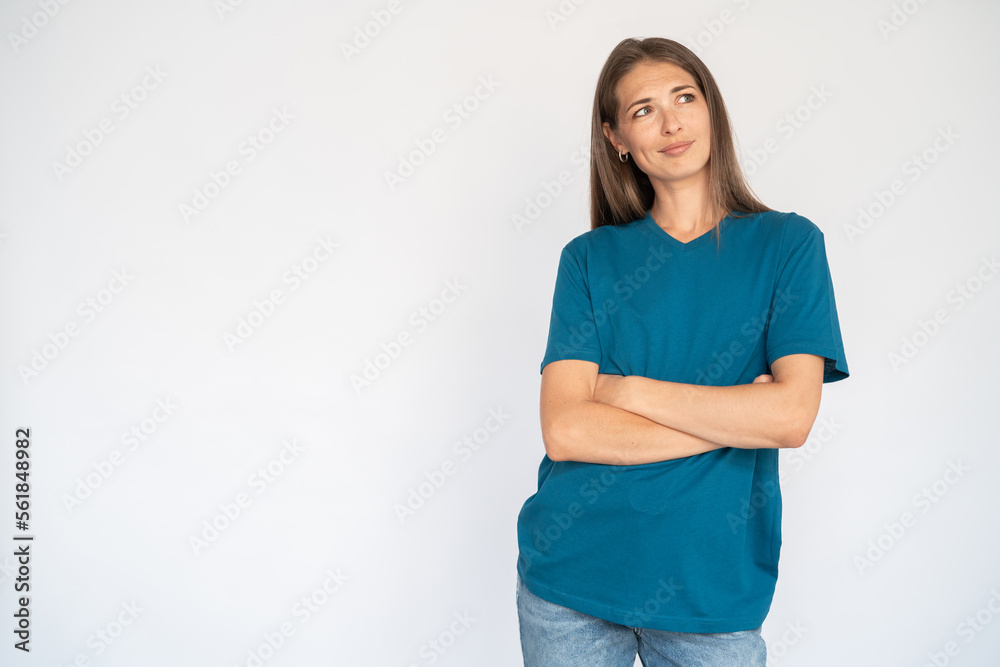 Confused Caucasian woman with crossed arms. Portrait of unsure young female model with brown hair in blue T-shirt looking away, considering special offer. Advertisement, doubt concept Confused Caucasian woman with crossed arms. Portrait of unsure young female model with brown hair in blue T-shirt looking away, considering special offer. Advertisement, doubt concept
