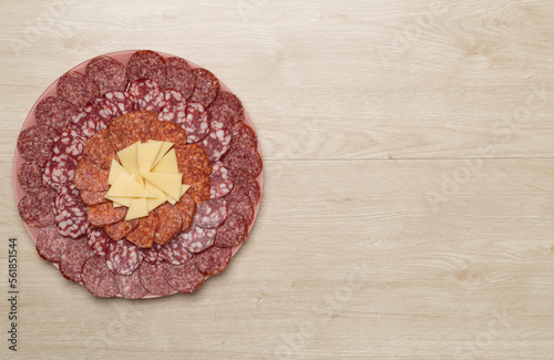 Plate with different smoked meat and cheese on wooden background, top view