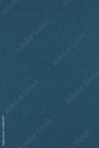 Dark blue colored paper texture. Tinted vertical background. Textured wallpaper. Large patterned surface. Fibers and irregularities are visible. Top-down