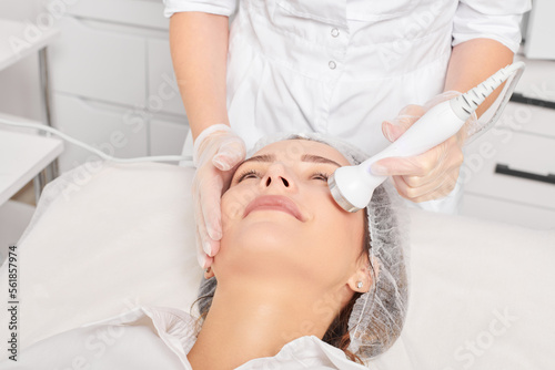 Cosmetologist makes ultrasound skin tightening for rejuvenation woman face using phonophoresis, anti aging cosmetic procedure with in beauty spa salon. Beautician makes ultrasonic skincare lifting