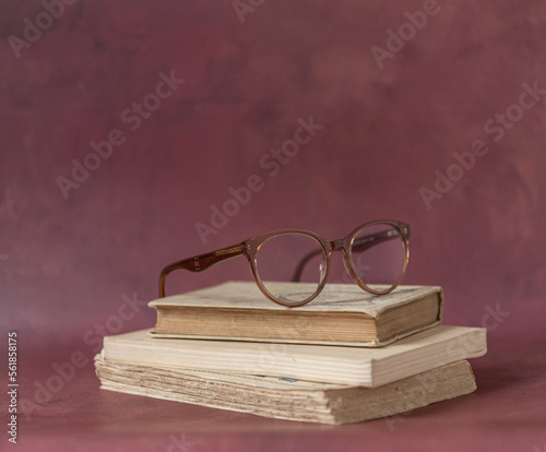 Pile de vieux livres et lunettes sur fond rouge