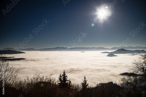 the sun standing high in the sky above a sea of clouds during a inversive weather situation in carinthia austria. photo