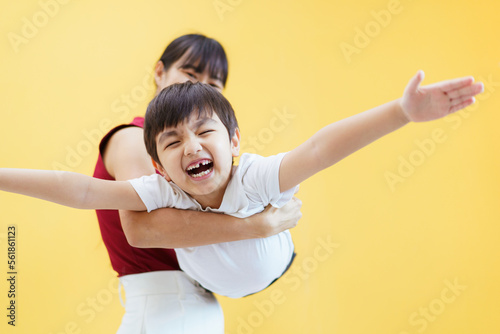 Obraz na plátně Happy cheerful Asian woman and a little young boy playing together, a woman piggyback or carrying a little boy on her back