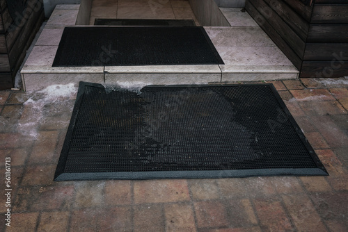 Door mat lying on tiled floor outdoor of house entrance