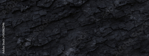 Black grunge rock panorama banner background. Dark gray fractured stone texture. Mountain cracks close-up backdrop with space for text and design