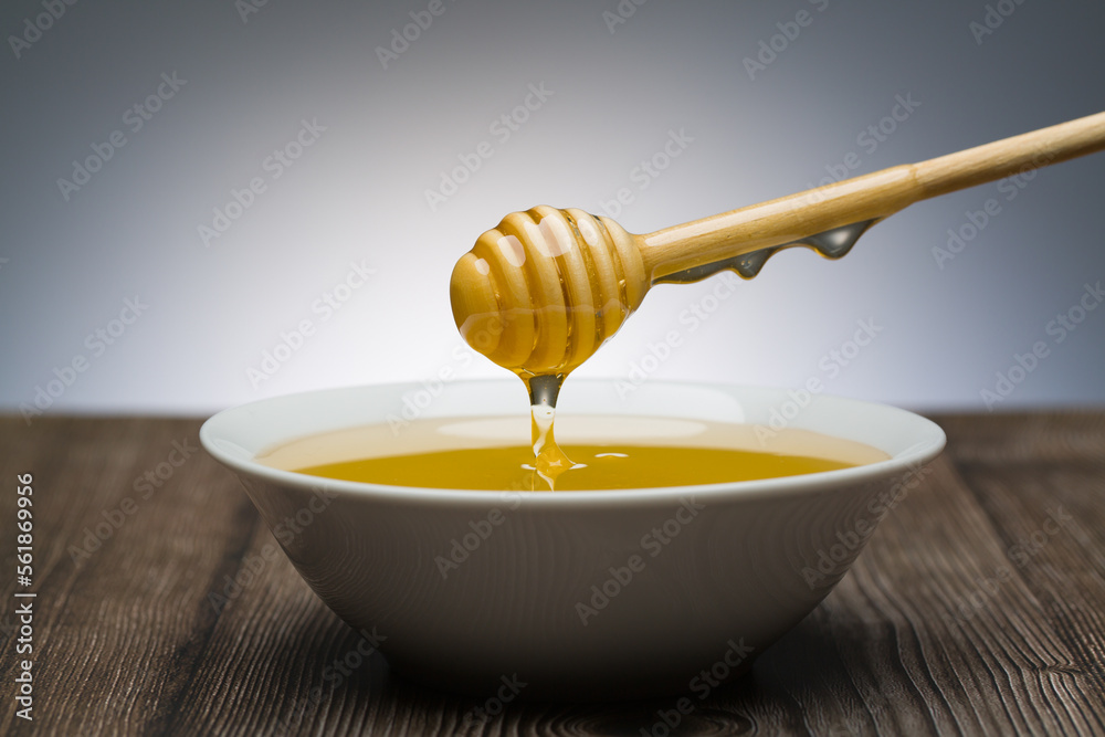 honey drips from the spoon into a white bowl honey drips from the spoon into a white bowl