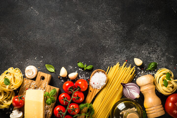 Pasta ingredients on black background. Raw Pasta, parmesan, fresh tomatoes and basil. Top view with copy space.