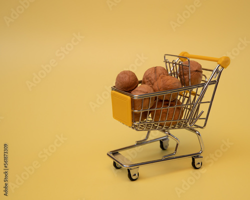 Walnuts in a mallard in a toy shopping cart on a yellow background
