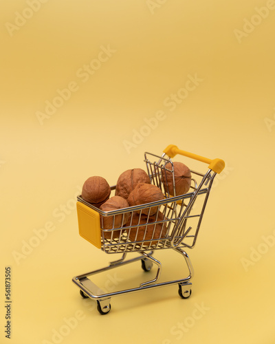 Walnuts in a mallard in a toy shopping cart on a yellow background