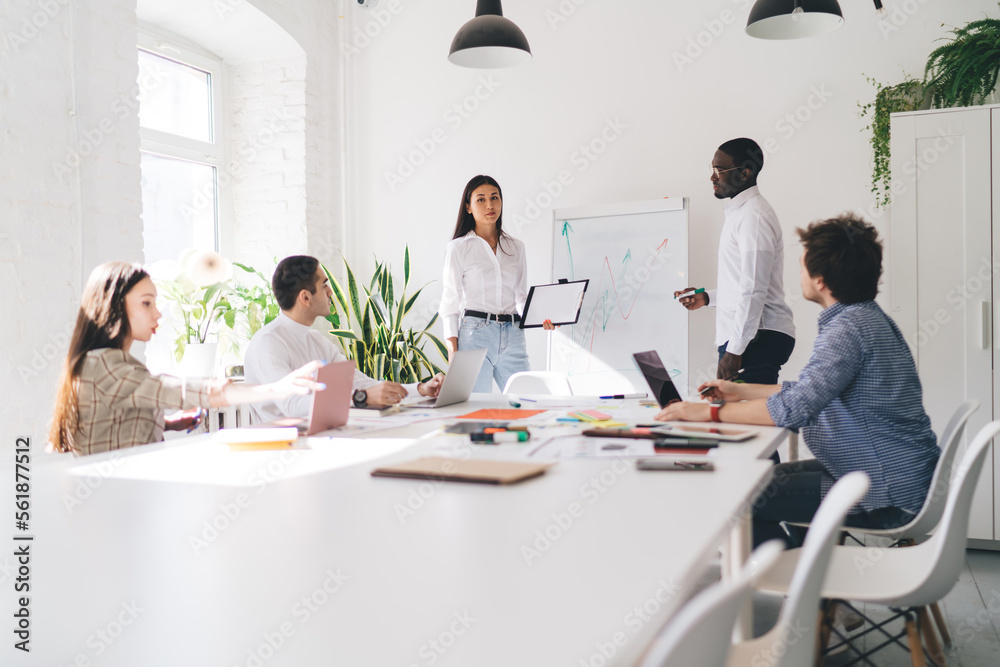 Diverse colleagues working together on business strategy in light workspace Diverse colleagues working together on business strategy in light workspace