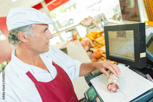 a butcher is weighing saucisson
