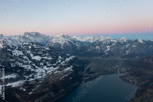 Amazing sunrise with a pink horizon over the peaks of the Swiss Alps over a mountain lake in Glarus Canton.