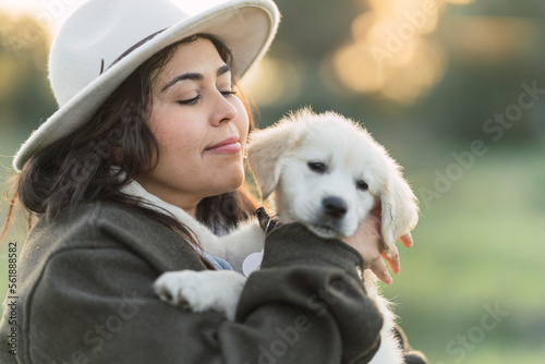 Mujer joven con cachorro de golden retriver posando feliz al atardecer en el campo