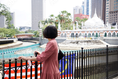 Woman standing on the side of River of Life viewing the Jamek Mosque in Kuala Lumpur, Malaysia on August 6, 2022