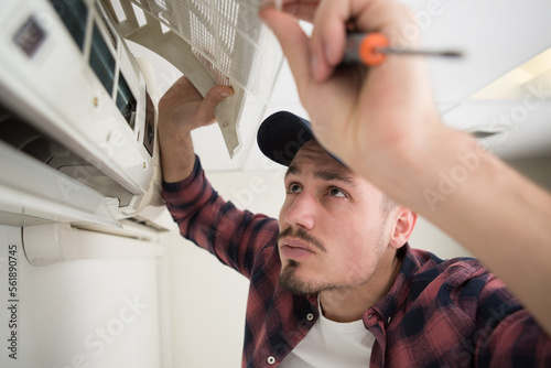 technician maintaining air-conditioning unit on the wall photo