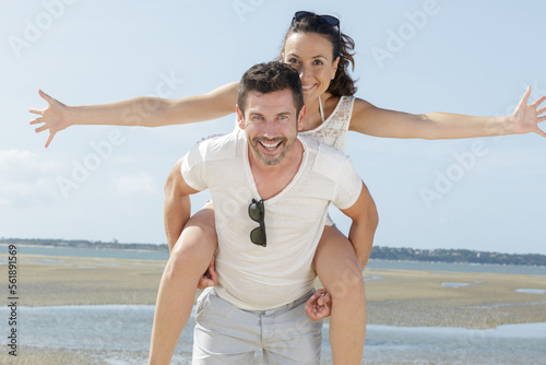 lovestory of beautiful couple piggybacking on the beach photo