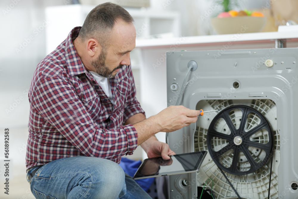man repairs an heating element of a washing-machine man repairs an heating element of a washing-machine