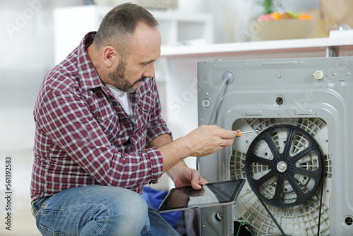 man repairs an heating element of a washing-machine