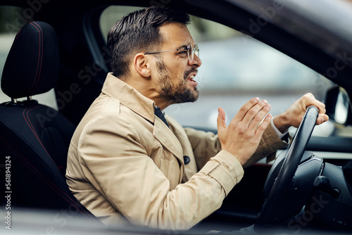 An angry man is cursing other drivers while sitting in a car and driving it.